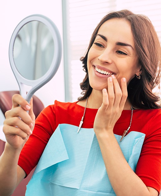 Woman in dental chair admiring reflection in mirror