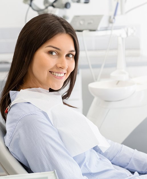 A brunette woman sitting in a dentist’s chair and smiling